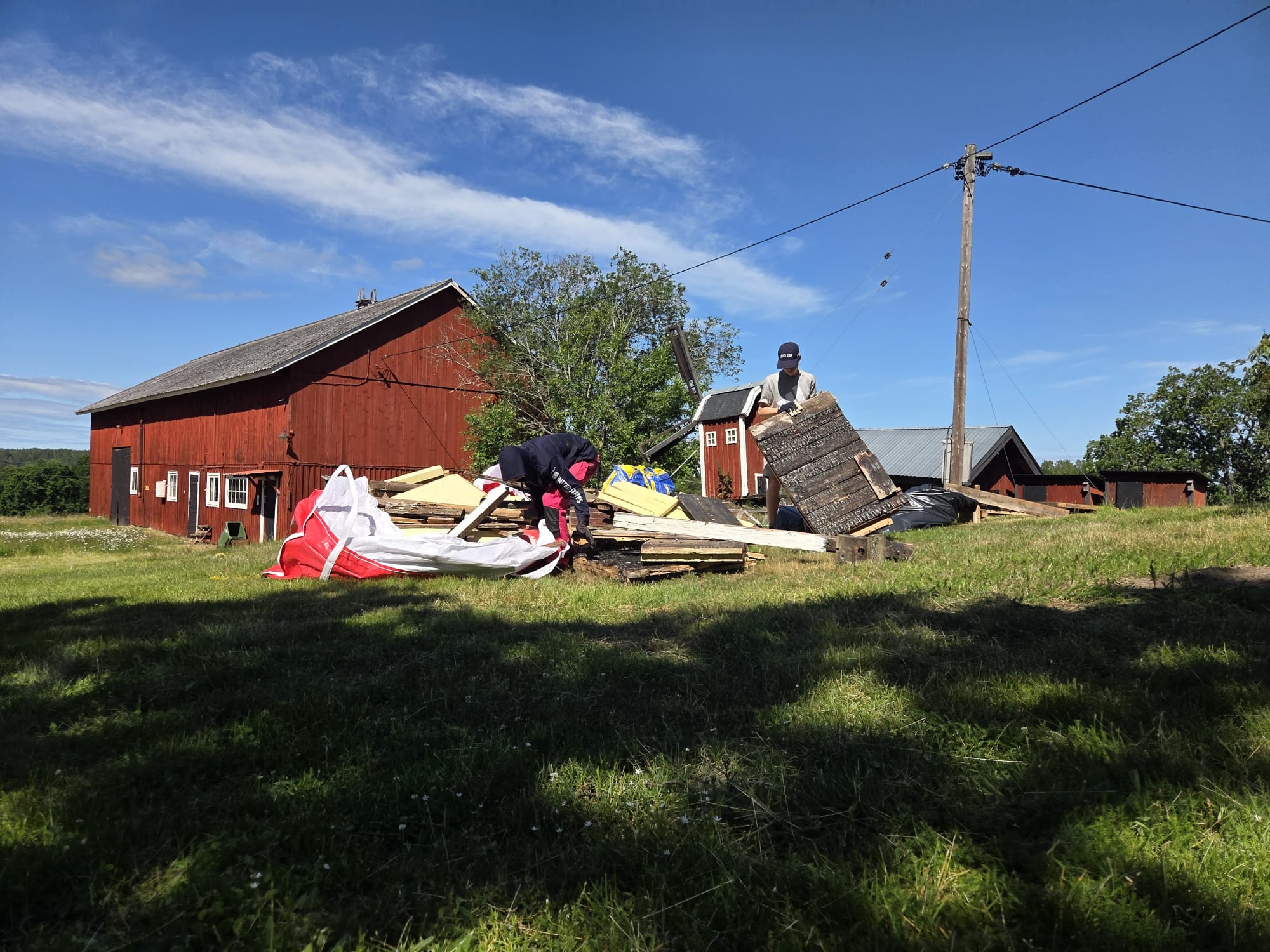 Ungdomar sorterar virke och byggavfall vid röd lada
