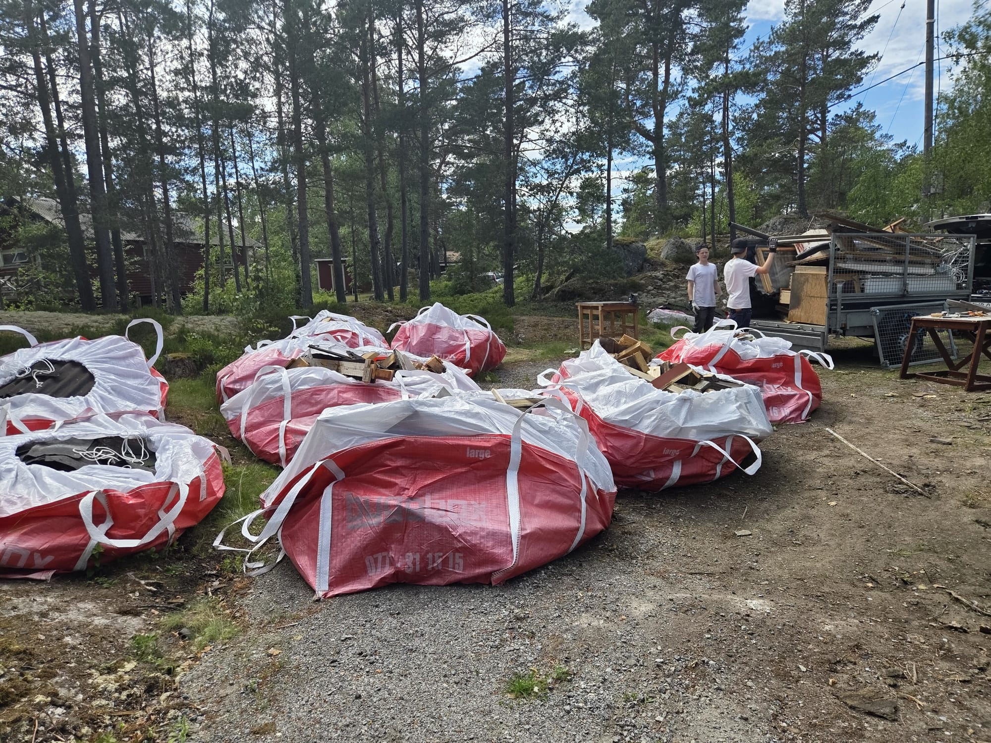 Storsäckar med avfall och släp lastat med skräp