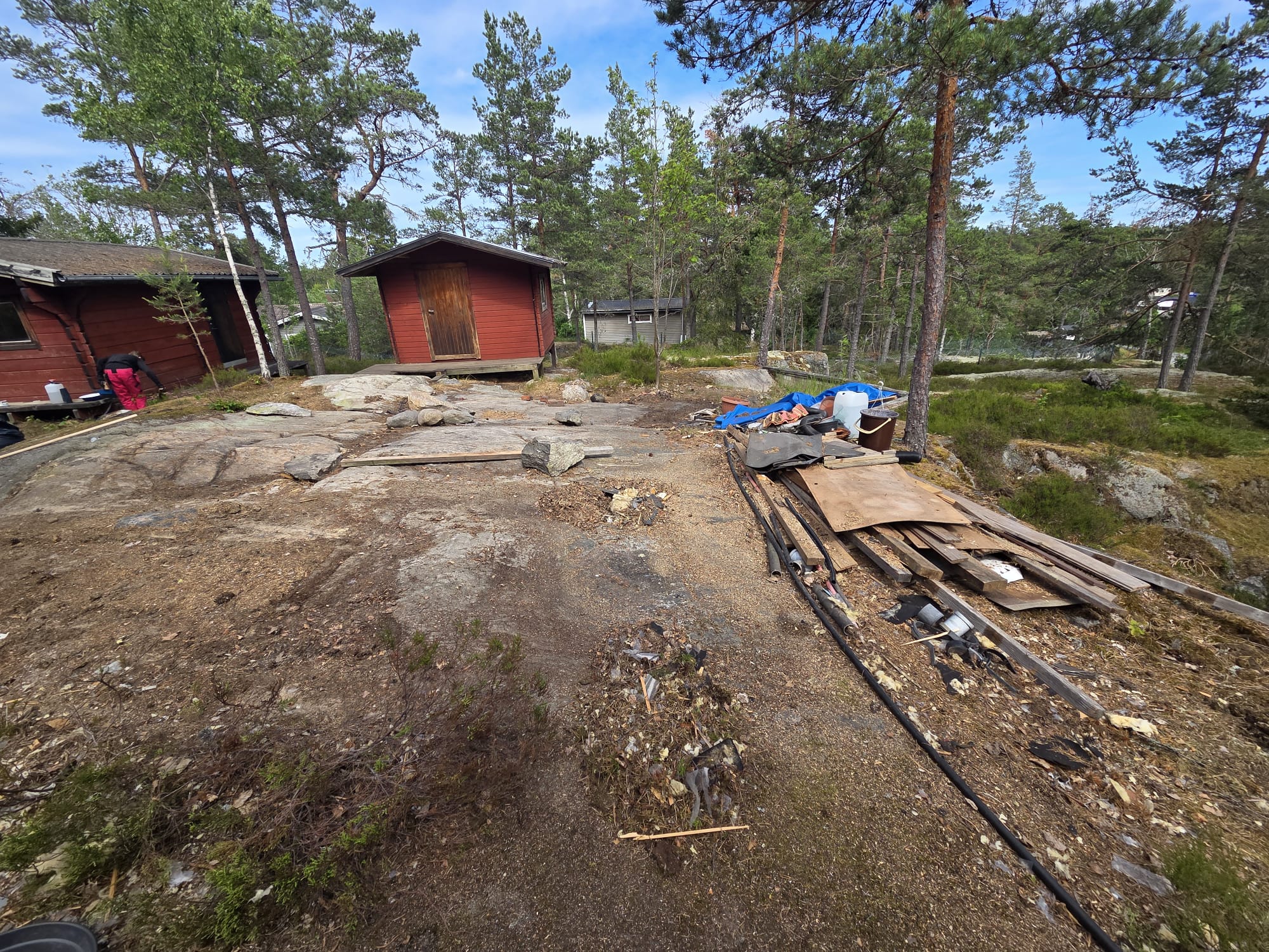 Röjd tomt vid rödmålad stuga i skärgården